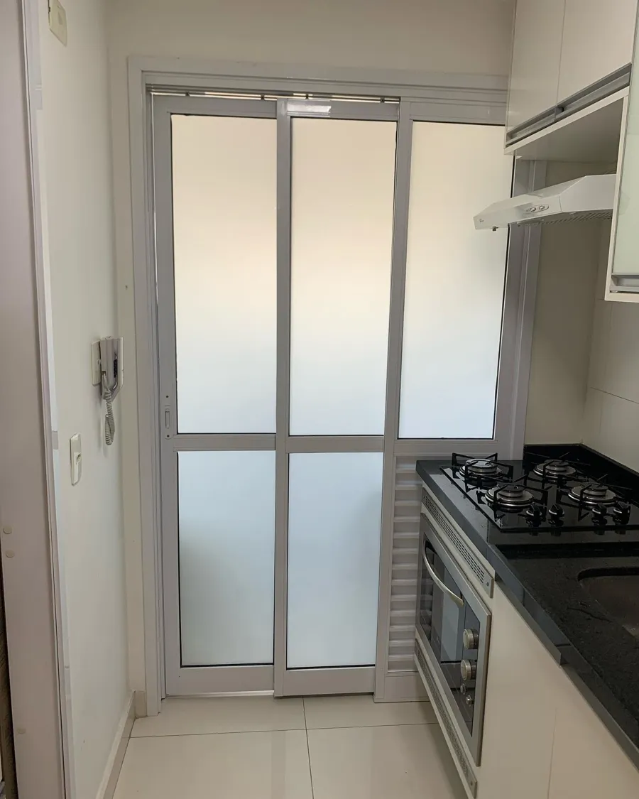 Porta de correr de cozinha com película jateada, que deixa a luz passar e esconde o que há do outro lado