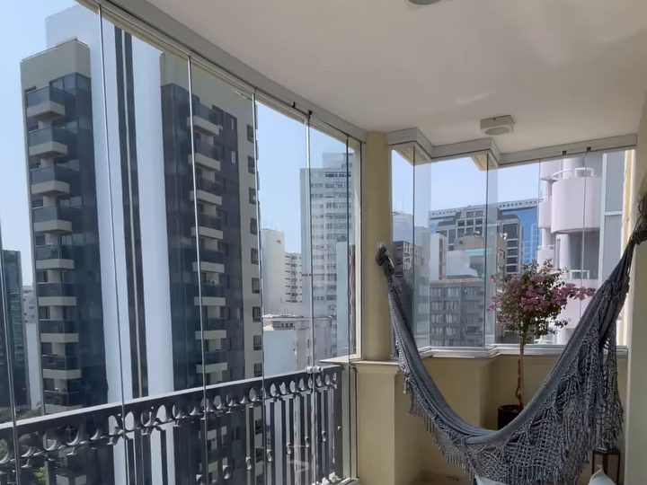 Sacada de apartamento fechada com vidro, com rede e vista da cidade